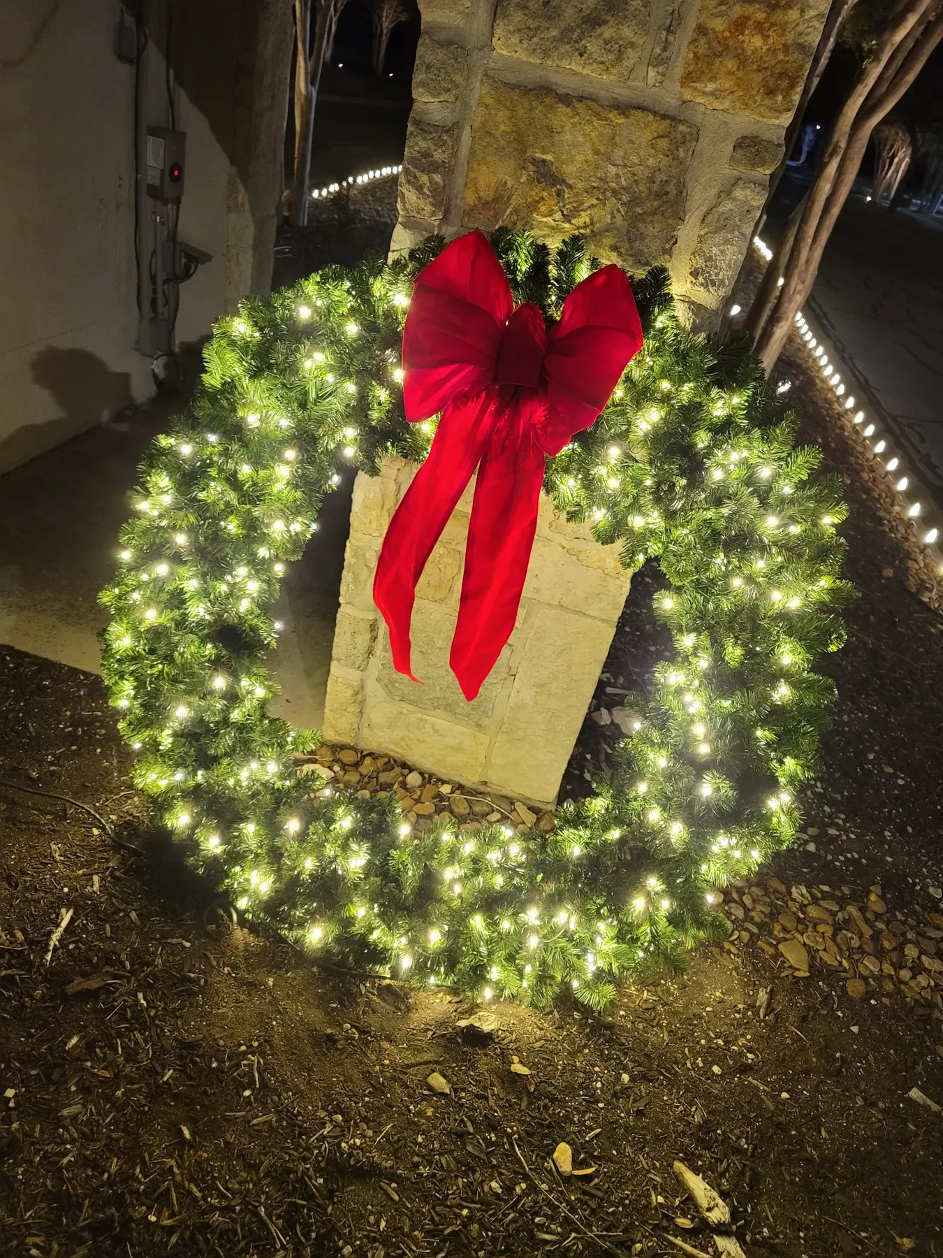 Large illuminated wreath with a red bow installed by Light It Up Holiday